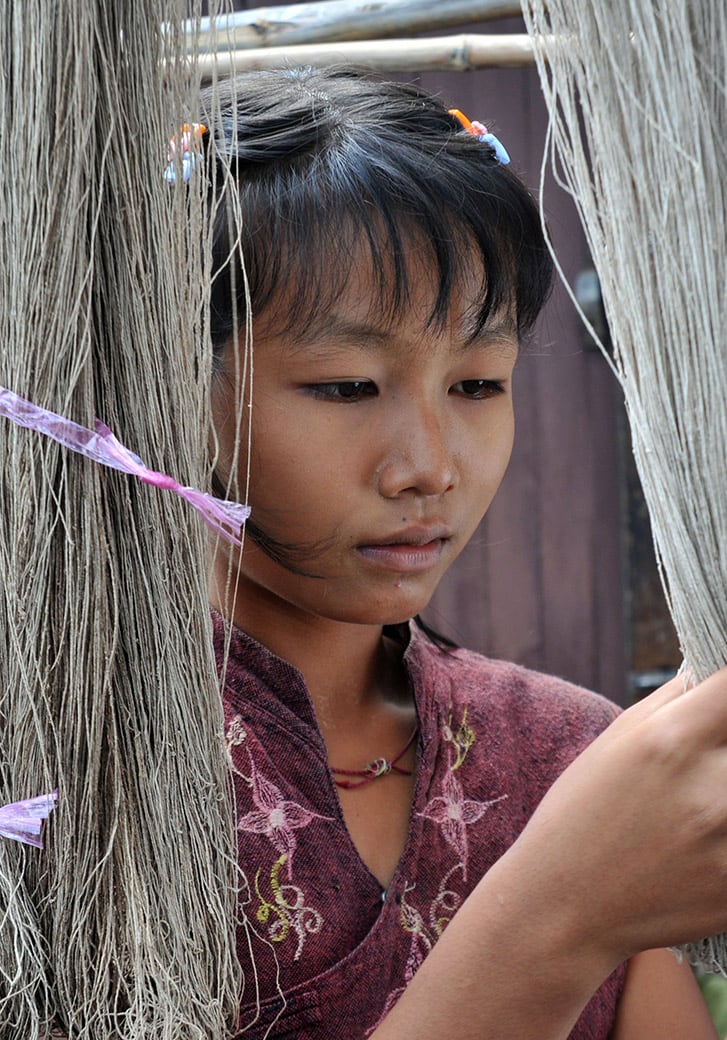 Young woman inspecting hanging threads made from lotus flower stems.